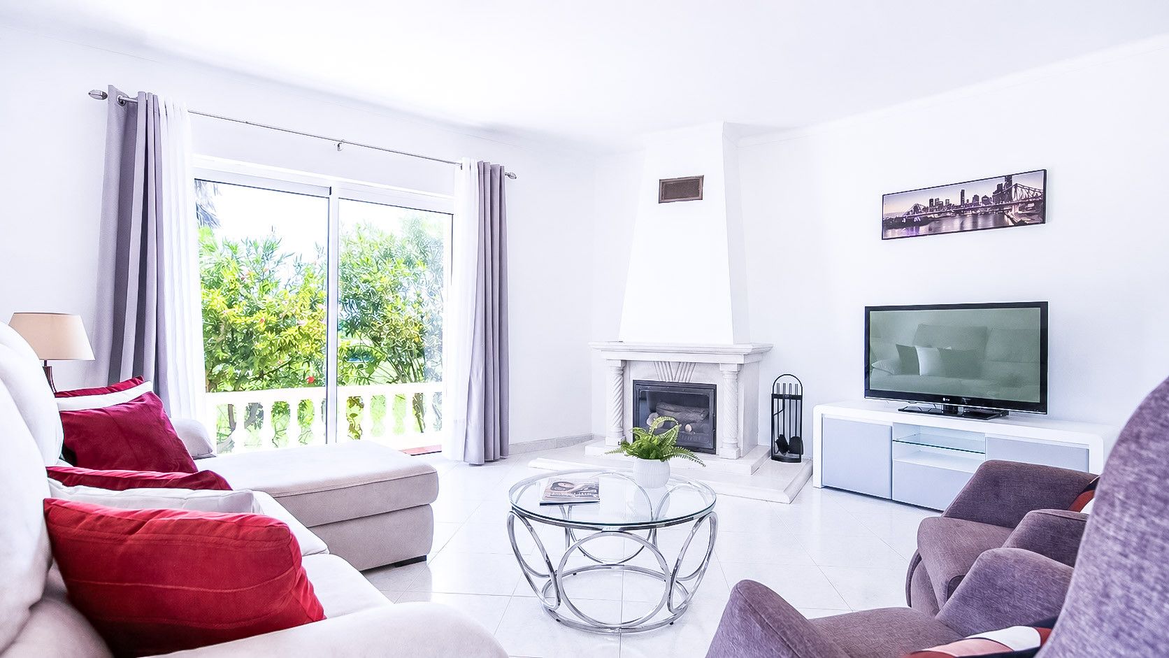 A modern living room with a fireplace, a television, and a balcony with curtains.