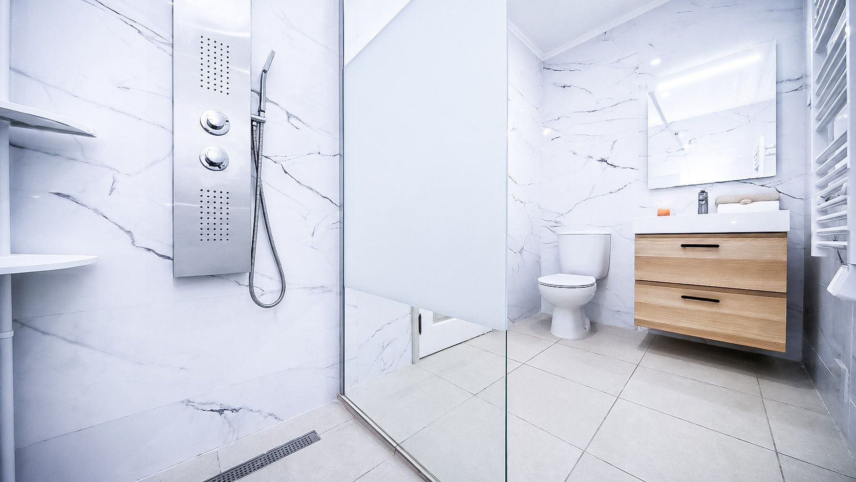 A modern bathroom with a glass shower enclosure, a toilet, and a vanity with a mirror.
