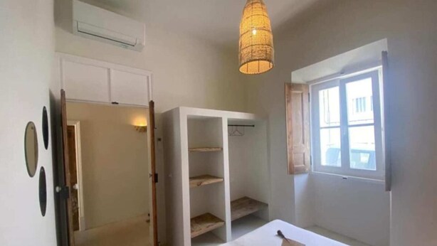 Ein Schlafzimmer mit Bett, Kleiderschrank, einer Hängelampe und einem Fenster.