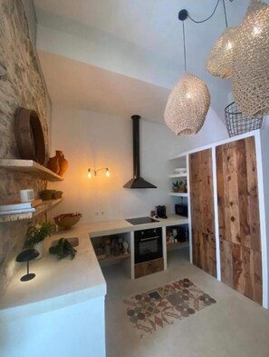 Una cocina moderna con una pared de acento de piedra, un horno empotrado y un armario de madera rústica.
