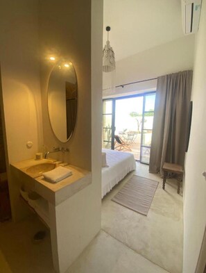 Une chambre avec un lit, une salle de bain avec un lavabo et une vue sur l’extérieur.