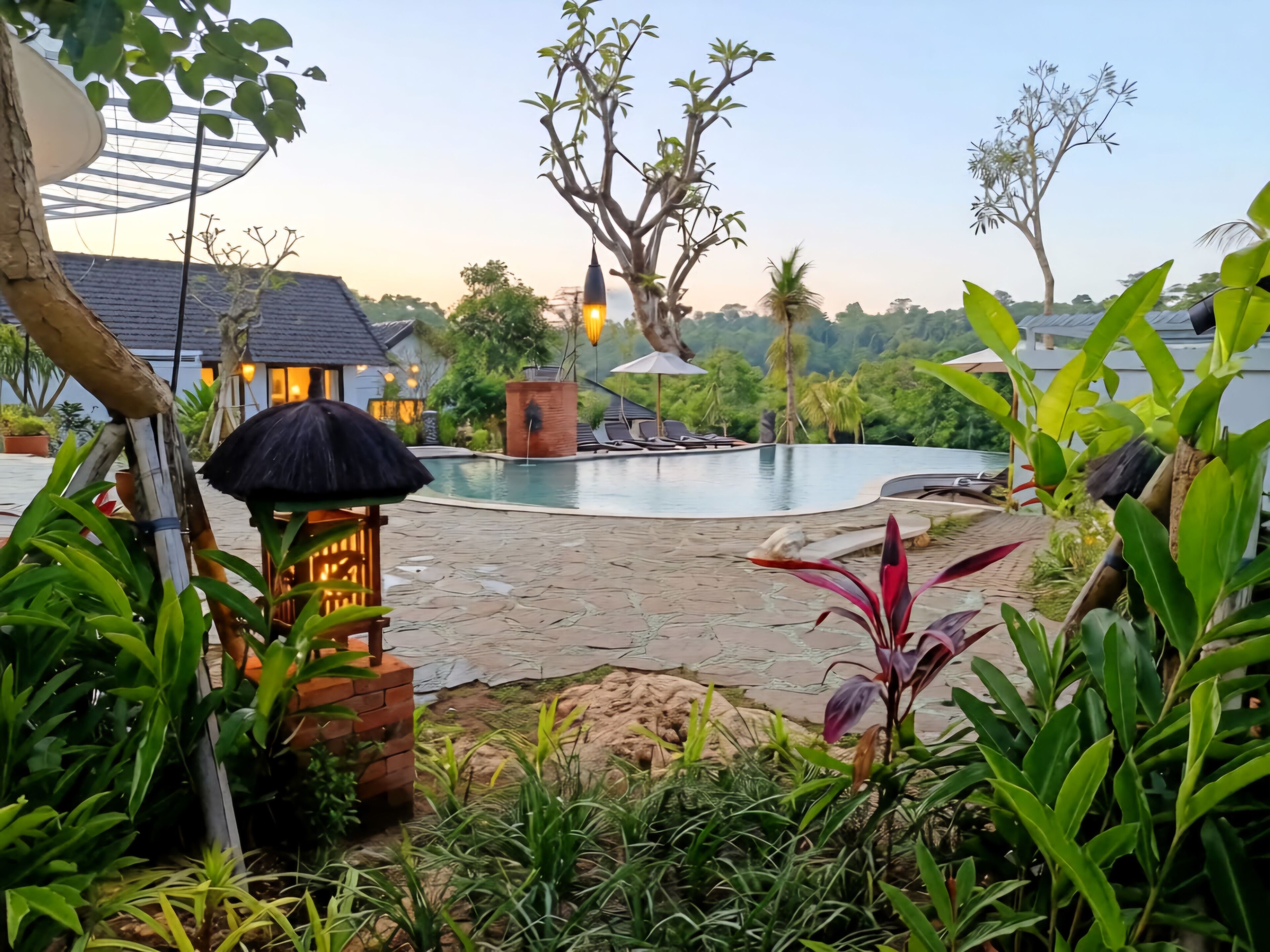 A pool area with lounge chairs, a brick structure, and lush greenery.