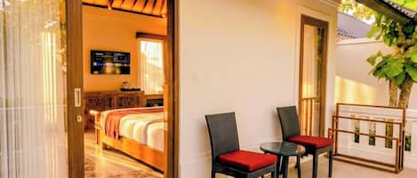Una habitación de hotel con cama, televisión y balcón con sillas y una mesa.