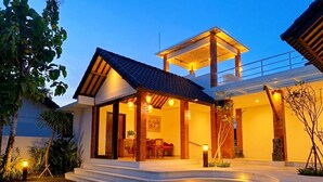 Een modern huis met een overdekte veranda, een eethoek en een trap die naar de ingang leidt.