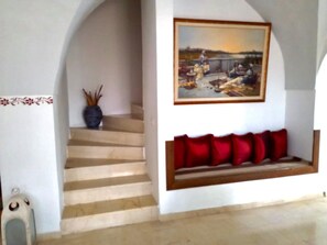Eine Treppe führt zu einer Empore mit einer Bank und einem Gemälde darüber.