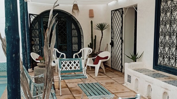 A covered outdoor seating area with metal furniture, a cactus, and a hanging light fixture. - Stylish villa in yasmine hamamet tourist zone, 5 min from carthage lind park. (Yasmine Hammamet)