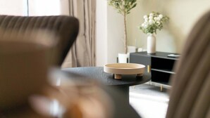 Ein modernes Wohnzimmer mit rundem Couchtisch, einer Couch, einem Topf mit Pflanze und einem flachbildfernseher an der Wand.
