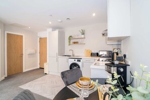 Un espace de vie compact comprenant une cuisine, un coin repas et un lave-linge.
