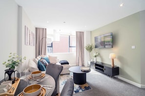 A modern living room with a sofa, coffee table, and TV. - Modern & Spacious 1 Bedroom Preston Apartment (Preston)