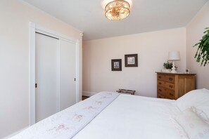 Une chambre à coucher avec un lit, une commode, une lampe et deux tableaux encadrés accrochés au mur.
