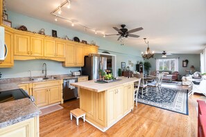 A spacious kitchen with wooden cabinets, a central island, and a dining area with chairs. - Shalom at Shenandoah | Pool, Sauna & Views (Swoope)