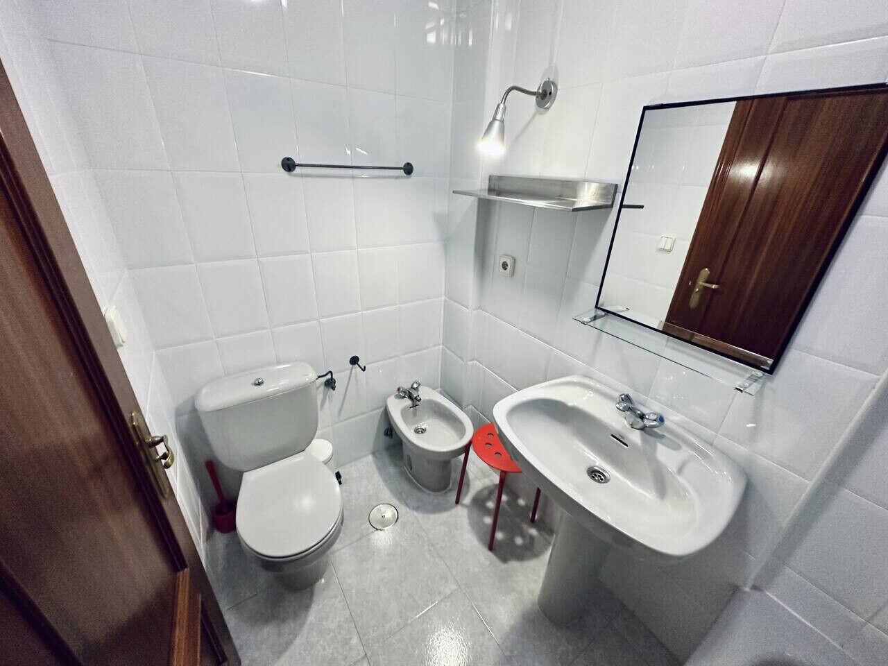 A bathroom with a toilet, bidet, sink, and mirror.