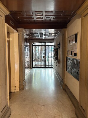 A hallway with a metal gate, a bulletin board, and a tiled floor. - Cozy near Reforma and Juarez (Ciudad de México)