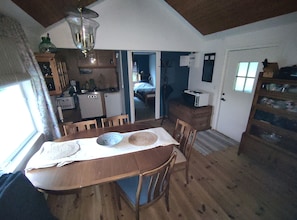 A compact kitchen with a microwave, a dining table with chairs, and a small refrigerator.