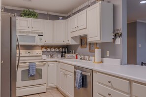 Eine Küche mit weißen Schränken, einer Mikrowelle, einem Backofen und einem Spülbecken.