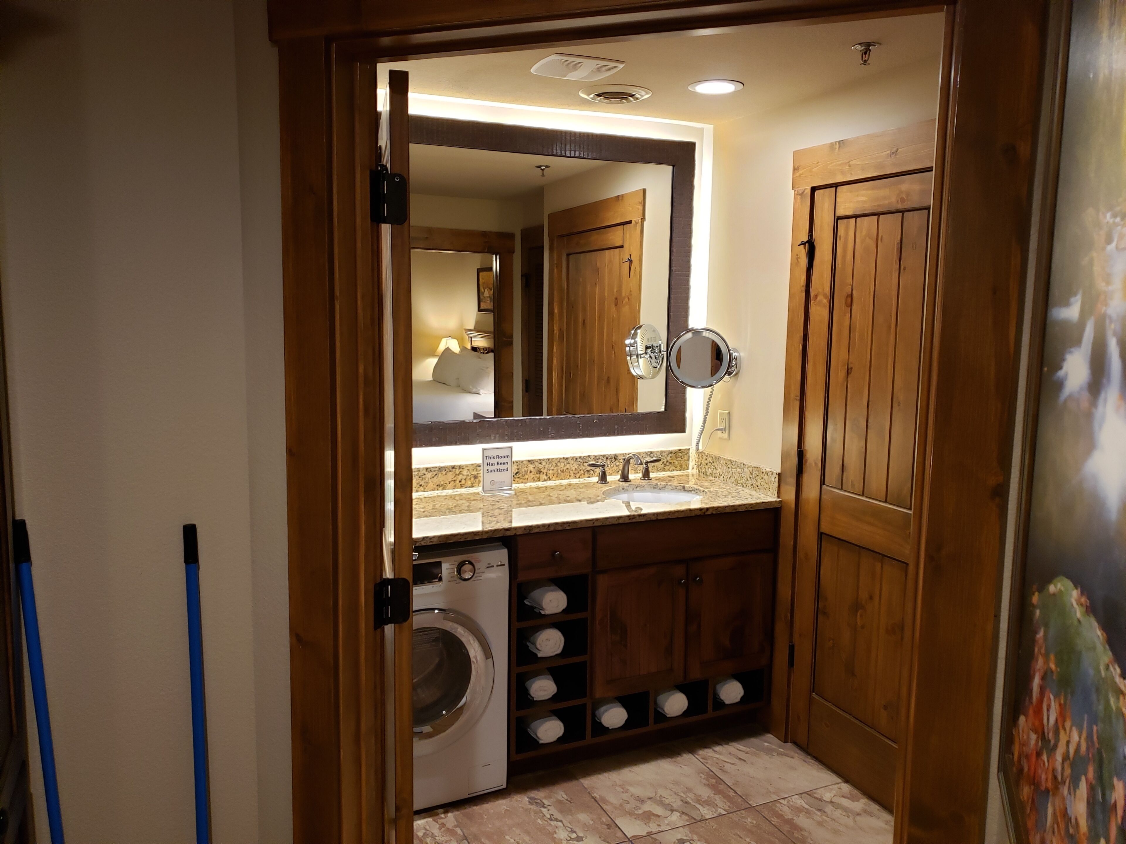 Une salle de bain équipée d’un lave-linge intégré, d’un lavabo et d’un grand miroir.