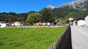 A rural village with houses, a grassy field, and mountains in the background. - Glungezer vacation apartment (Thaur)