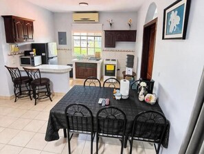 A compact kitchen with a dining area, including a table with chairs, a microwave, a refrigerator, and a sink.