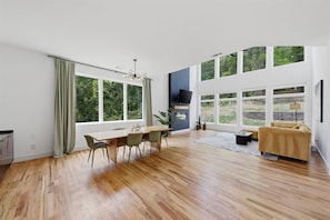 Ein geräumiges Wohnzimmer mit großem Esstisch, einer Couch und einem Fernseher.