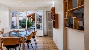 Un coin repas avec une table en verre, des chaises et une vue sur une terrasse extérieure, accessible par des portes vitrées.