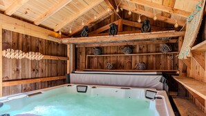 Une salle de spa en bois, dotée d’un bain à remous, d’étagères en bois et d’objets décoratifs.