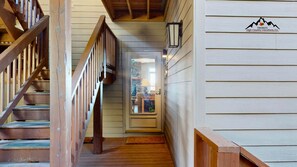 A wooden staircase leading to a room with a door, a window, and a logo on the wall. - Reserve 4D • Your Happy Place (Sugar Mountain)