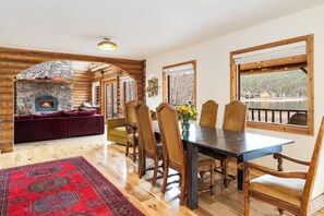 Un coin repas agrémenté d’une cheminée en pierre, d’une table à manger en bois et de chaises.