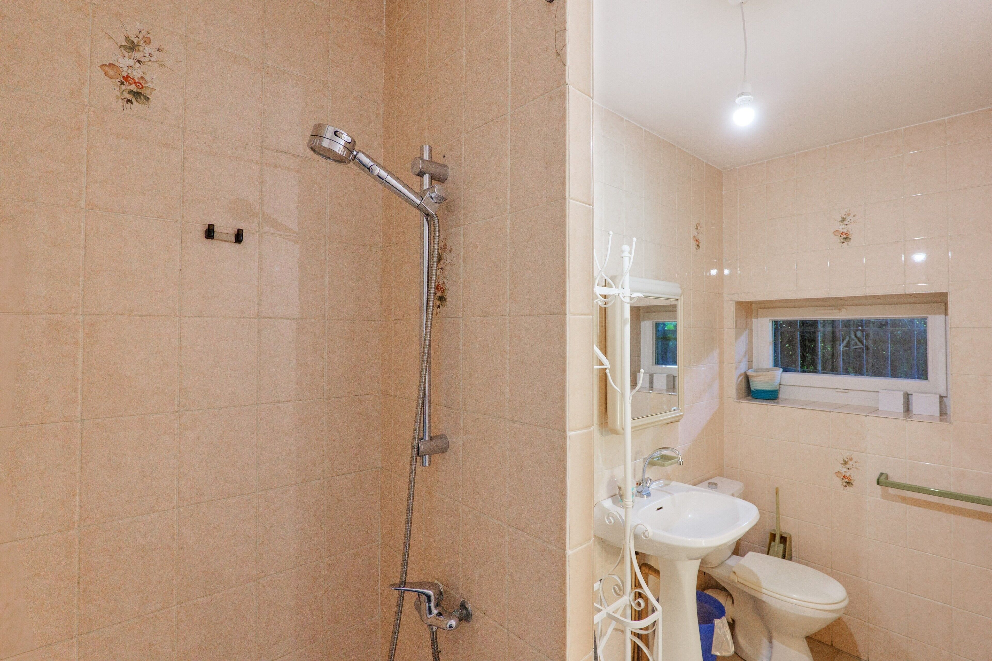 A bathroom with a shower, toilet, sink, and window.