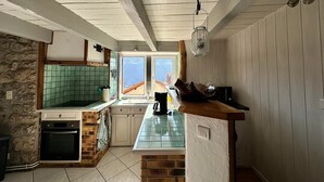 Una cocina con pared de piedra, techo de madera y vistas al exterior.