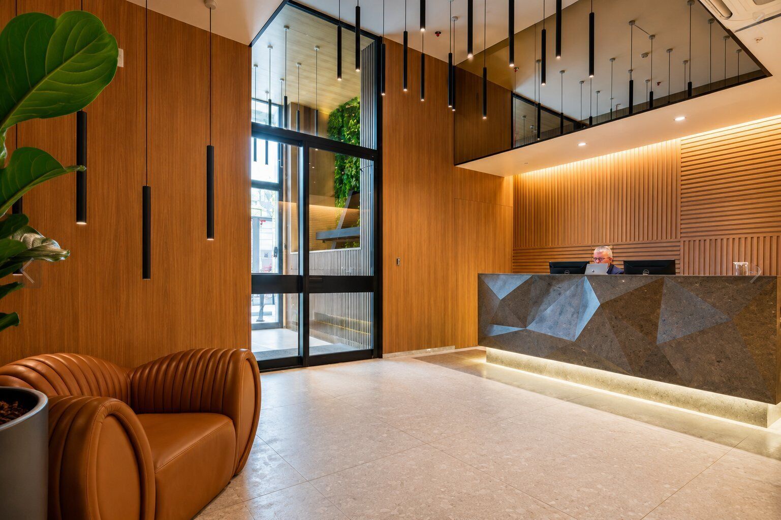 A modern reception area with a wooden reception desk, leather seating, and a glass door leading outside.