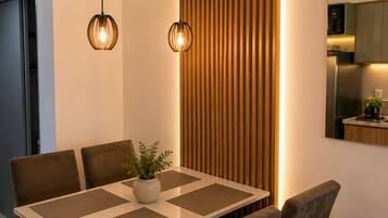 A modern dining area with a wooden table, cushioned chairs, and pendant lighting.