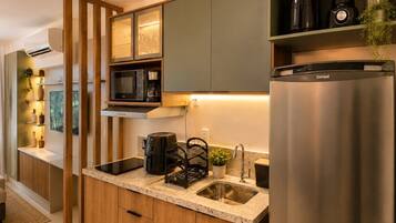 A modern kitchen with a built-in microwave, coffee maker, and a stainless steel refrigerator.