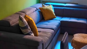 A living room with a sectional sofa, a window with blinds, and a chair. - Segreto Estense: Dormi a un Passo dalla Storia (Ferrara)