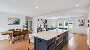 Une cuisine moderne dotée d’un grand îlot central, d’une table à manger en bois et d’un coin salon bleu.