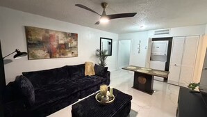 A living room with a dark sofa, a coffee table with decorative items, a ceiling fan, and a wall-mounted mirror.