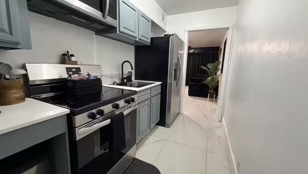 A compact kitchen with a stove, oven, sink, and a refrigerator.
