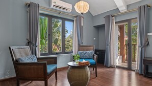 A room with two wicker chairs, a round table, and a large window with curtains. - Sweet Daisy Retreat (Da Nang)