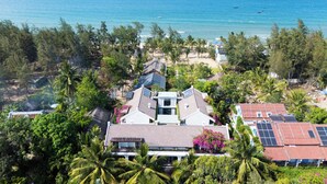 A coastal residential area with houses, palm trees, and a beach. - Sweet Daisy Retreat (Da Nang)