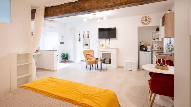 Una habitación de hotel moderna con una cama, un escritorio pequeño, un televisor y una kitchenette.