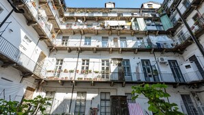 Un edificio de varios pisos con balcones, ventanas y algunas macetas.