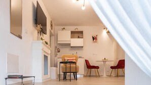 Una sala de estar moderna con un sofá, dos sillones rojos, una mesita, un televisor de pantalla plana y una chimenea.