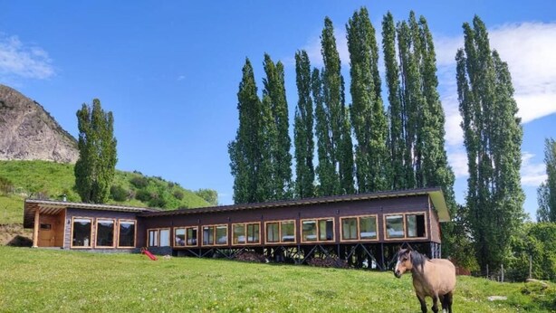 Un edificio con un lungo corridoio e un cavallo in un prato erboso.