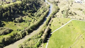 Vista aérea de un río serpenteando a través de un paisaje rural con edificios dispersos y campos verdes.