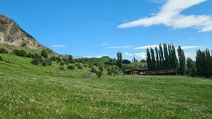 Paisaje rural con un tren, una montaña y cielo despejado.