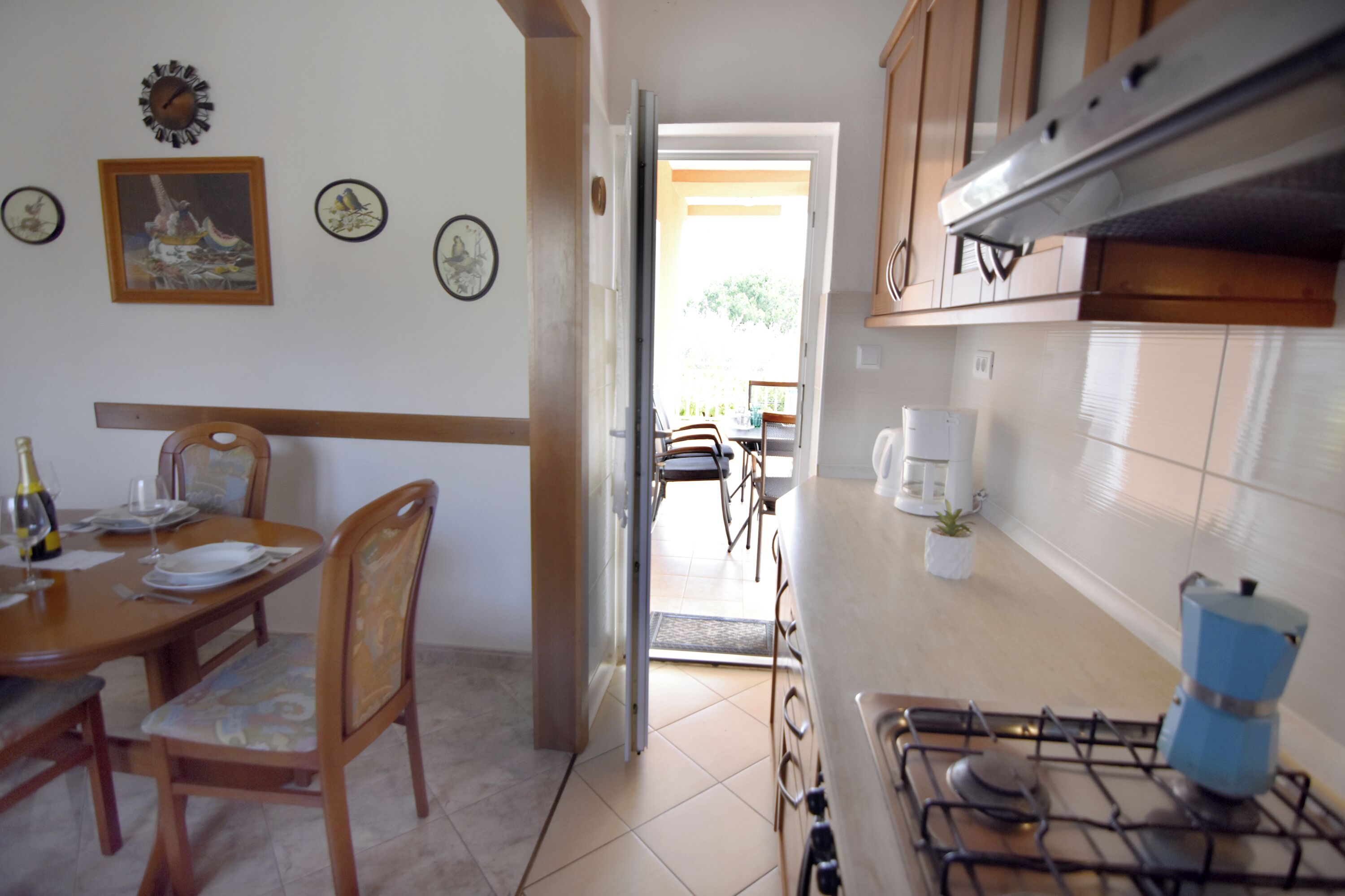 Una cocina con estufa, armarios y comedor con sillas y una mesa.