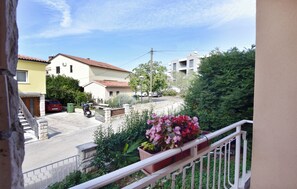 A residential street with houses, a parked car, and a balcony with potted plants. - Precious Accommodation for Four Guests in Umag (Umag)