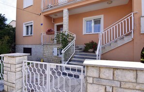 Ein zweistöckiges Gebäude mit Balkon, Treppe und einem verschlossenen Eingang.