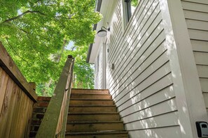A wooden staircase leading up to a house with white siding and a mailbox on the right.