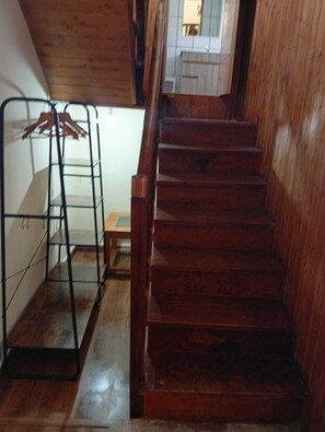 Una escalera de madera con barandilla metálica y piso de madera.