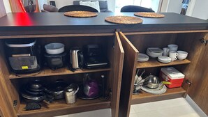 Una cucina con un pensile in legno, una macchina da caffè, un bollitore e un frigorifero rosso.
